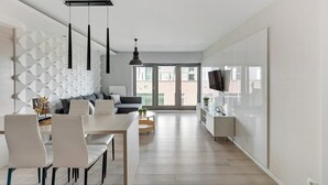 Cozinha moderna com espaço de jantar, sofá e televisão.