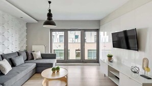 Uma sala de estar moderna com sofá, mesa de centro redonda, TV e varanda com vista.