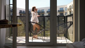 A balcony with a person standing, two chairs, and a table. - Portovo 193 | Jacuzzi Suite | Perfect for Couples (Gdańsk)