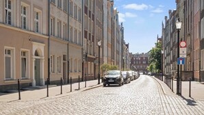 Eine Kopfsteinpflasterstraße gesäumt von historischen Gebäuden, eine schmale Straße und ein geparktes Auto.