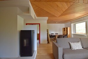 A modern living room with a flat-screen TV, a grey sofa, wooden flooring, and a wooden ceiling. - CROZZON view Apartment MhD (Madonna di Campiglio)