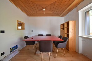 Ein Konferenzraum mit Holzbalkendecke, einem roten Tisch und sechs Stühlen.
