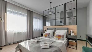 Ett modernt hotellrum med en stor säng, ett sängbord, en garderob och utsikt över staden.