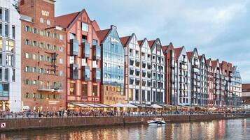 Ein Hotel am Wasser mit einer Reihe traditioneller Gebäude im europäischen Stil, einem Restaurant im Erdgeschoss und einem Boot, das im Wasser liegt.