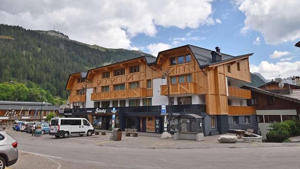 Ett hotell med en träfasad, flera balkonger och en bergskedja som bakgrund.