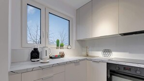 Eine moderne Küche mit weißen Schränken, einem eingebauten Backofen und einer Kaffeemaschine auf der Arbeitsfläche.