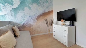 A bedroom with a large wall mural, a flat-screen TV, a white dresser, and a sofa. - Old Town Sieroca | Comfortable Stay (Gdańsk)