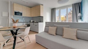 A modern apartment with a kitchen, dining area, and a sofa with cushions. - Old Town Sieroca | Comfortable Stay (Gdańsk)