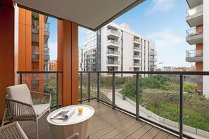 A balcony with wicker chairs and a table, overlooking a residential area with modern buildings. - Brabank 10 | Riverside & Balcony | Parking (Gdańsk)