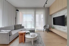 A modern living room with a sofa, coffee table, and TV. - Brabank 10 | Riverside & Balcony | Parking (Gdańsk)