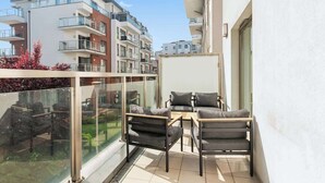 Ein Balkon mit zwei Stühlen und einem Tisch, mit Blick auf ein Wohngebiet mit mehrstöckigen Gebäuden.