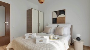 Ein Hotelzimmer mit einem Bett, einem Kleiderschrank, einem Nachttisch und einem an der Wand hängenden Kunstwerk.