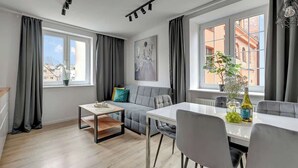 Ein modernes Wohnzimmer mit einer Couch, einem Esstisch und großen Fenstern.