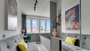 Ein modernes Wohnzimmer mit grauen Sofas, einem kleinen Tisch und Kunstwerken an den Wänden.