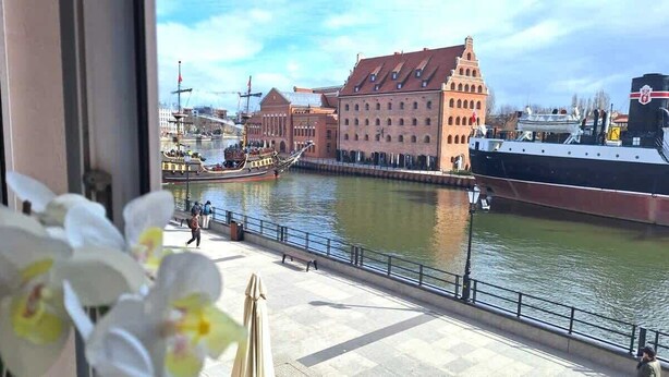 Ein Fluss mit einem historischen Gebäude und einem großen Schiff, das andockt.