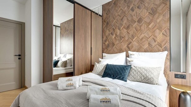 Una camera d'hotel con un letto, un armadio, uno specchio e una parete con motivo geometrico.