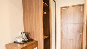 Una habitación con un armario de madera, una mesita de madera con una tetera, y una puerta.