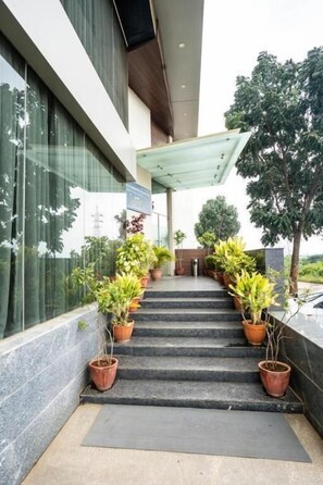 A staircase leading to a building entrance with potted plants on either side. - Samasth Palatial Hotel (Mysore)