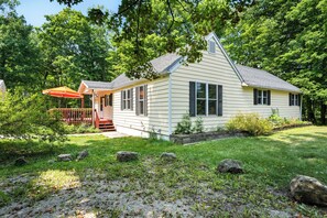 A single-story house with a porch, a covered outdoor seating area, and a well-maintained lawn.