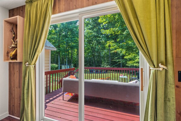 A room with a sliding glass door leading to an outdoor deck with a red railing and a sofa.