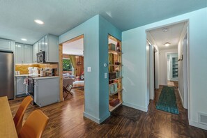 A modern kitchen with wooden cabinets, a built-in microwave, and a dining area with a table and chairs.