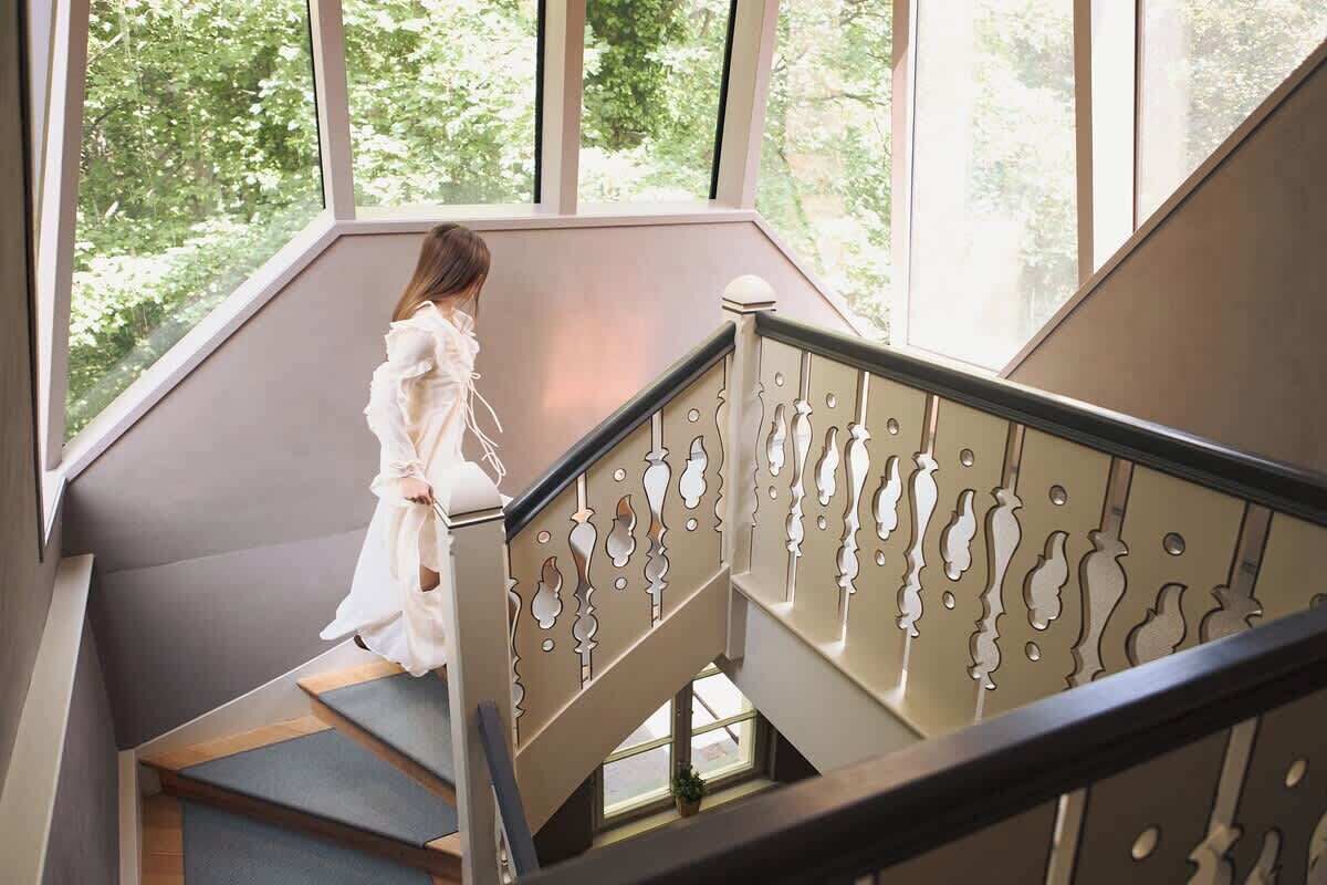 Eine Treppe mit Geländer, eine Person steigt hinab und ein Blick auf grüne Vegetation im Freien.