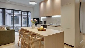 Une cuisine moderne dotée d’un îlot central, de meubles en bois et d’une grande fenêtre offrant une vue sur la ville.