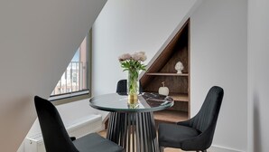 Ein moderner Essbereich mit einem Glastisch, schwarzen Stühlen, einer Blumenvase und einem Holzboden mit Dekorationen.