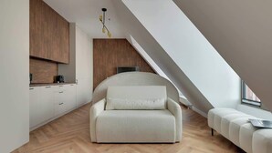 Ein modernes Schlafzimmer im Loft-Stil mit Fischgrätparkett, einer Couch, einem Bett und einer Küchenzeile mit Holzausbau.