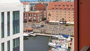 Ein Yachthafen mit anglegerten Booten, ein Gebäude mit rotem Dach und ein weißes Gebäude mit großen Fenstern.