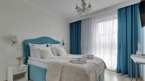 Ein modernes Hotelzimmer mit einem Bett, Nachttischen, einem Fernseher und einem Fenster mit Vorhängen.