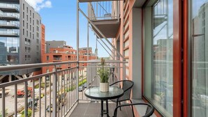 Ein Balkon mit Tisch und Stühlen, einem Blumentopf und Blick auf die Stadtlandschaft.