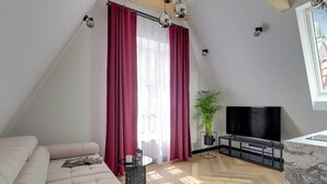 Een moderne woonkamer met een bank, een televisie, een bijzettafeltje en een plant in pot.