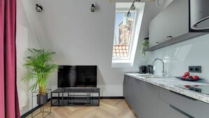 Een moderne keuken met een televisie, een plant en een raam met uitzicht op gebouwen.