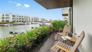 En balkon med udsigt over en kanal, både og moderne bygninger.