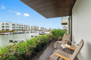 Uma varanda com vista para um canal, barcos e edifícios modernos.