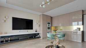Eine moderne Küche mit Flachbildfernseher, Essbereich mit rundem Tisch und Stühlen sowie integriertem Backofen.