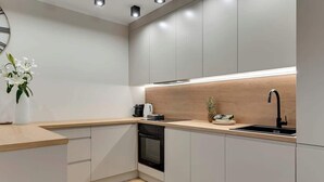 A modern kitchen with a wooden countertop, built-in oven, and a black faucet. - Latarników 84 | Perfect Stay (Gdańsk)