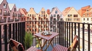 A balcony with a table and chairs, overlooking a row of multi-story buildings with balconies. - Granaria D507 | Best Location (Gdańsk)