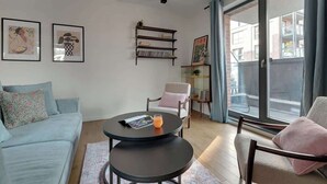 Moderni olohuone, jossa on sohva, pyöreä pöytä, jonka päällä on lehti ja lasi appelsiinimehua, kirjahylly ja liukuovi, joka johtaa ulos.