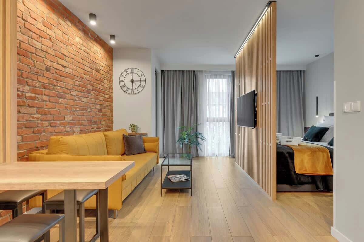 Una sala de estar moderna con pared de ladrillo, un sofá, una mesa de centro y un televisor.