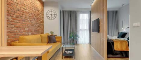 Una sala de estar moderna con pared de ladrillo, un sofá, una mesa de centro y un televisor.