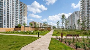 Een wooncomplex met hoge gebouwen, een verharde looppad en aangelegde groenvoorzieningen.