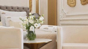 A hotel room with a tufted headboard, a round gold table, and white floral arrangements. - Jacuzzi Mirror Suite Nadmotławie Estate 111 (Gdańsk)