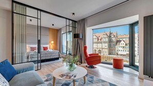 Ein modernes Hotelzimmer mit einem großen Bett, einer Couch, einem Couchtisch und Blick auf die Stadt.
