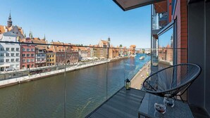Ein Balkon mit Blick auf einen Fluss, Gebäude und einem Stuhl.