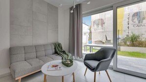 Ein modernes Wohnzimmer mit einem grauen Sofa, einem runden Couchtisch und einem grauen Sessel.