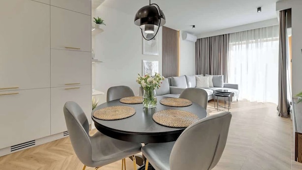 A modern living room with a dining area, a sofa set, and a large window with curtains. - Nadmotławie Estate 129 | Riverside | Sauna & Gym (Gdańsk)
