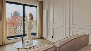 Une pièce avec une grande fenêtre, une table ronde, un canapé et un radiateur.