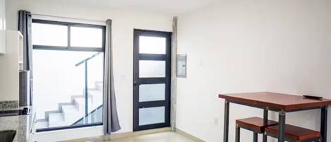 Una habitación con una encimera de cocina, una mesa de comedor y una escalera que sube a un piso superior.